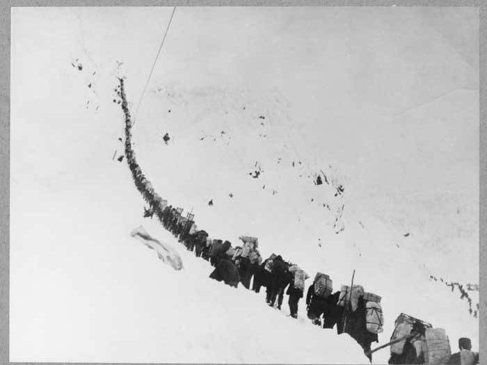 A single file of packers climbing the ice staircase cut into the Chilkoot Pass, 1898.
