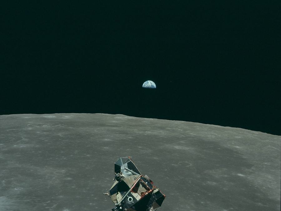 Eagle's ascent stage rising above the lunar surface, the Earth small on the black horizon behind it.