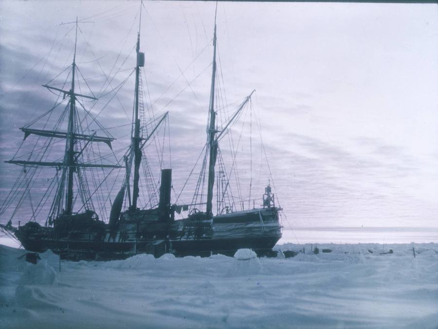 The ship Endurance held fast in pack ice at twilight, rigging dark against a violet sky.